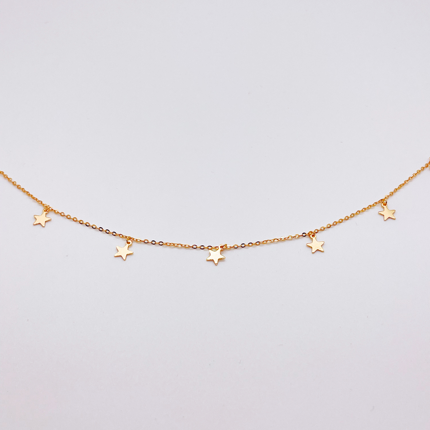 Gold anklet with star charms on a white background