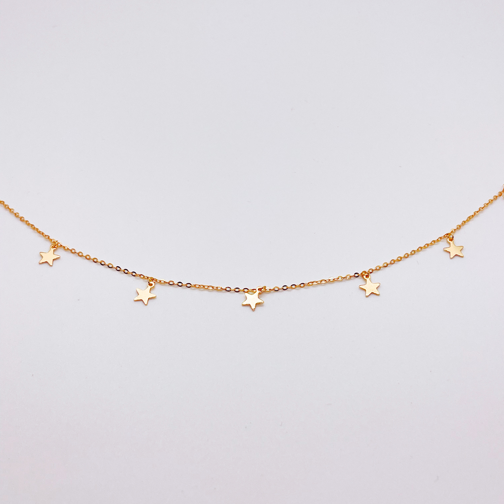Gold anklet with star charms on a white background